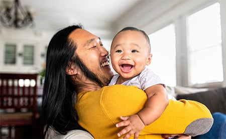 A happy baby being held by his laughing father