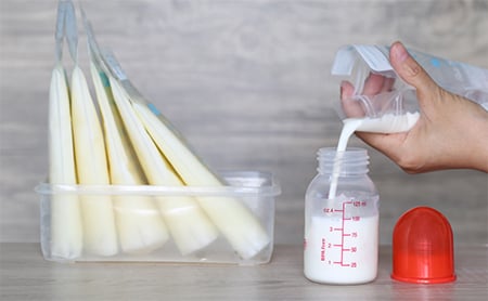 A bag of breast milk is emptied into a bottle