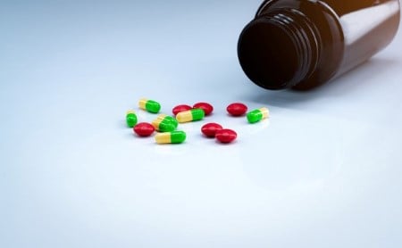 Colorful capsules and pills spilling out of a brown medicine bottle