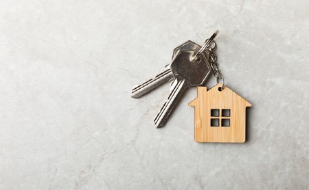 Keys on a key chain that is shaped like a house