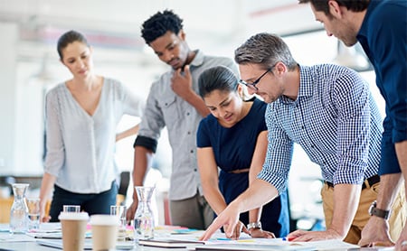 A group of colleagues work on a project at a conference table