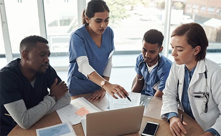 A group of doctors and nurses collaborate at a conference table