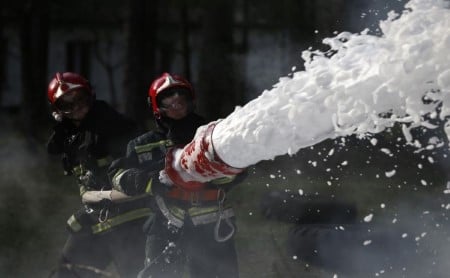 Firefighters using fire-retardant foam to put out fire with a hose