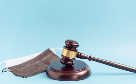 Gavel, block, and two PPE face masks on a light blue background