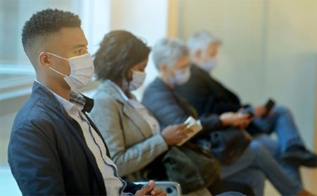 Socially-distanced people wearing masks in a waiting room