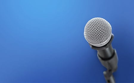 Blue background with microphone in microphone stand to the right side