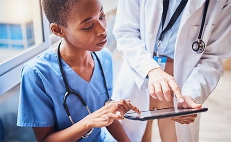 A nurse and doctor review a patient's medical chart on a tablet