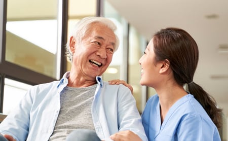 A nurse and her elderly patient smile at one another