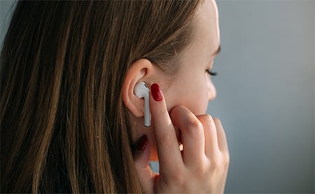 Over-the-shoulder view of a woman putting in earbud headphones