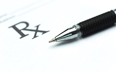A pen resting on a paper with a visible "Rx" symbol.