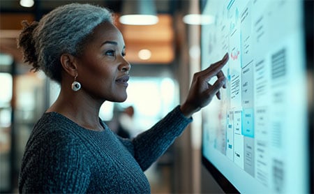 A woman interacting with a large touch screen in a modern office setting.