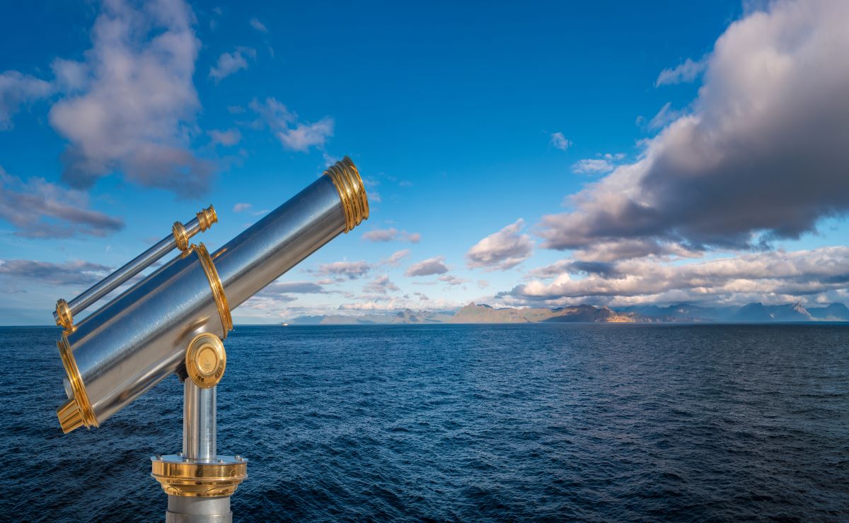 Silver telescope mounted in front of open water