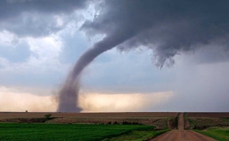 Tornado storm cell and funnel cloud in a rural field, near a dirt road