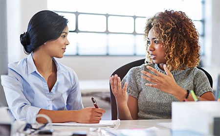 Two women talking at a conference table